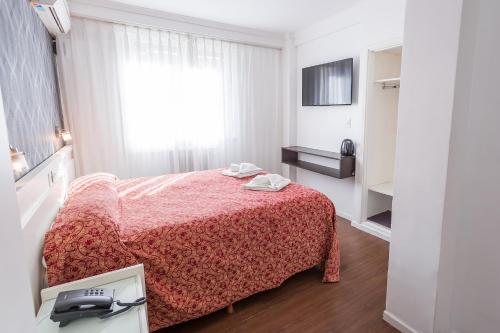 a bedroom with a bed with a red bedspread and a window at Estocolmo Hotel by bund in Mar del Plata