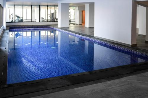 a swimming pool with blue tiles in a building at Noor Amwaj Hotel & Apartment in Manama