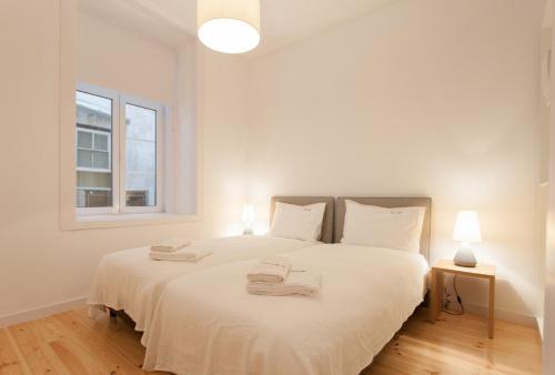 a bedroom with a white bed with two towels on it at FLH Baixa Luxury Apartment in Lisbon