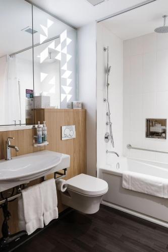 a bathroom with a toilet and a sink and a tub at Alt Hotel Saskatoon in Saskatoon