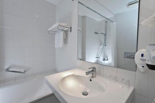 a white bathroom with a sink and a mirror at Wyndham Garden Potsdam in Potsdam