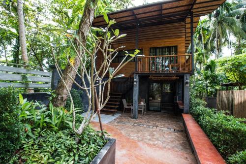 a wooden house with a balcony in a garden at Andalay Beach Resort Koh Libong in Ko Libong