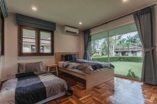 two beds in a bedroom with a large window at F5 3 Bed Rooms Beach house, full kitchen in Rayong