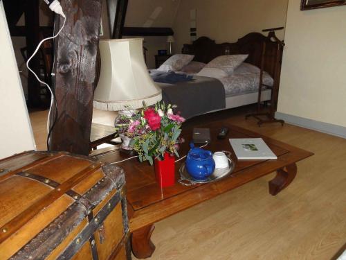 a room with a table with a lamp and flowers on it at La demeure aux Pins in Lourdes