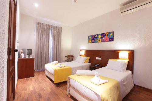 a hotel room with two beds with towels on them at Residencial Mar e Sol in Costa da Caparica