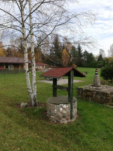 a stone bench with a roof next to a tree at Pod Sową in Drawsko Pomorskie