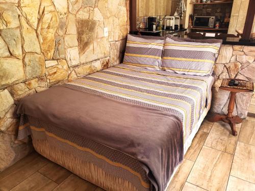 Ce lit se trouve dans un dortoir doté d'un mur en pierre. dans l'établissement Lotus Guest House, à Florianópolis