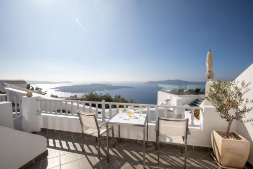 a balcony with a table and chairs and a view of the ocean at Santorini View Studios - Firostefani Caldera in Firostefani