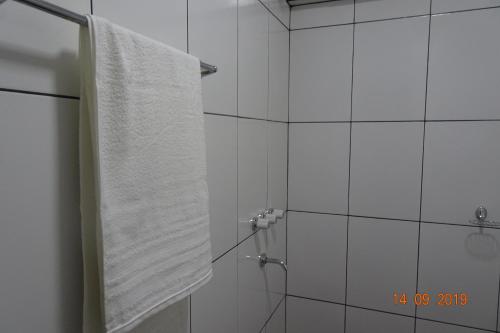 a bathroom with a shower with a white towel at Mediterráneo Suites in Puerto Iguazú