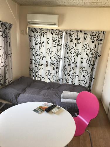 a living room with a white table and a pink chair at Utopia Wakamiya 106 / Vacation STAY 5141 in Fukuoka