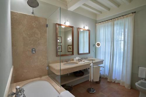 W łazience znajduje się wanna, umywalka i lustro. w obiekcie Castello di Fighine w mieście San Casciano dei Bagni