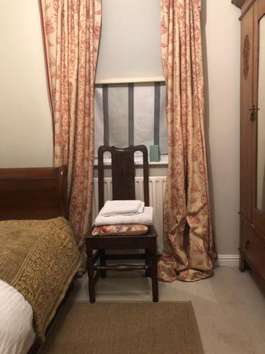 a chair sitting in front of a window with curtains at Victoria Villas in London