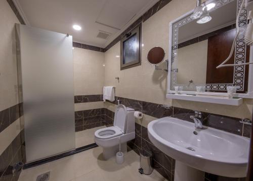 a bathroom with a sink and a toilet and a mirror at شقق حديقة الزهور 2 للشقق المخدومة in Yanbu