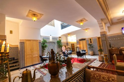 ein großes Wohnzimmer mit Tischen und Stühlen in der Unterkunft Riad Al Makan in Fès