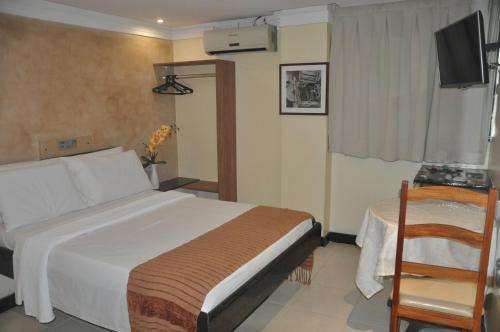 um quarto com uma cama, uma mesa e uma televisão em Hotel Sempre Bahia em Salvador