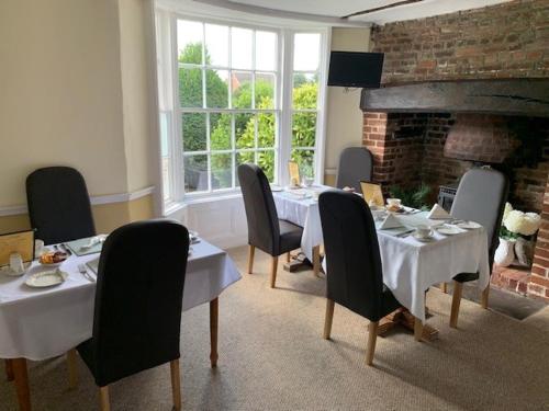a dining room with tables and chairs and a fireplace at The Beaumont in Sittingbourne