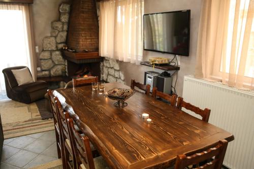 a wooden dining room table with chairs and a television at Holiday Home in the Center of the Village in Pávliani