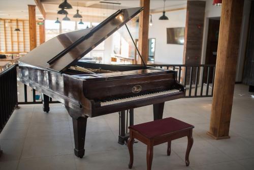 a piano with a stool in a room at Best Western Patagonia in Puerto Natales