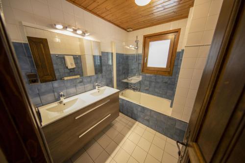 y baño con lavabo, bañera y espejo. en Le Château, en Morzine