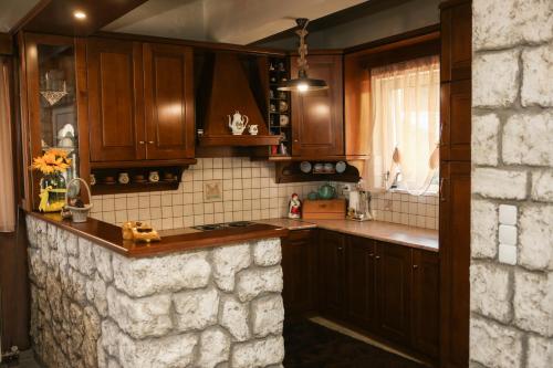 a kitchen with wooden cabinets and a stone wall at Holiday Home in the Center of the Village in Pávliani