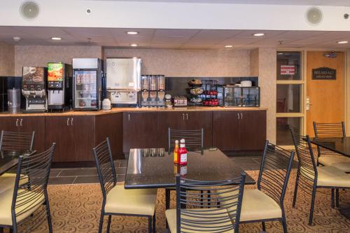 a restaurant with a table and chairs and a refrigerator at Ramada by Wyndham Plymouth Hotel & Conference Center in Plymouth
