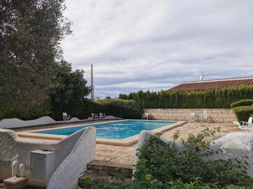 - une piscine dans une cour entourée de chaises dans l'établissement Apartment Hibiscus, à Cala Pi