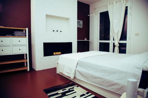 ein Schlafzimmer mit einem weißen Bett und einem Kamin in der Unterkunft CASA DI ATOS fiera district in Bologna