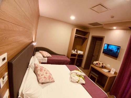 a hotel room with two beds and a television at Hotel Smeraldo in Qualiano
