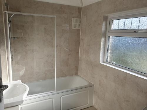 a bathroom with a white tub and a sink at Elegant house 10 minutes walk to wembley stadium in London