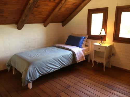 a bedroom with a bed and a nightstand and two windows at La Ranita Negra in La Paloma