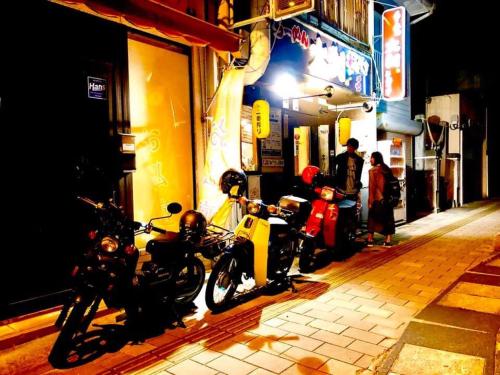 a couple of motorcycles parked on a street at night at Guest house daisho oshiro asobi in Matsue