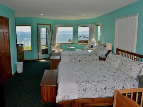 a bedroom with a bed and a table and windows at Driftwood Inn in Homer