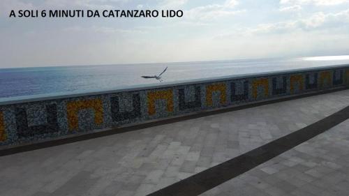 a bird flying over a wall next to the ocean at La Dimora Degli Artisti in Catanzaro