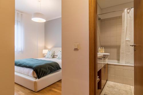 um quarto com uma cama e uma casa de banho com uma banheira em River View Apartment by Lisbon Heart em Lisboa