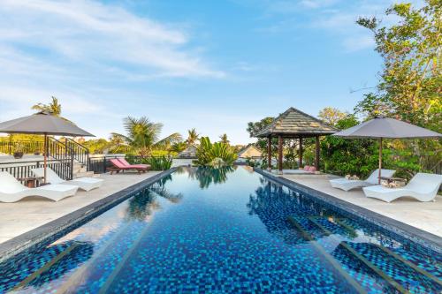 an image of a swimming pool at a resort with chairs and umbrellas at Umah CinCin in Canggu