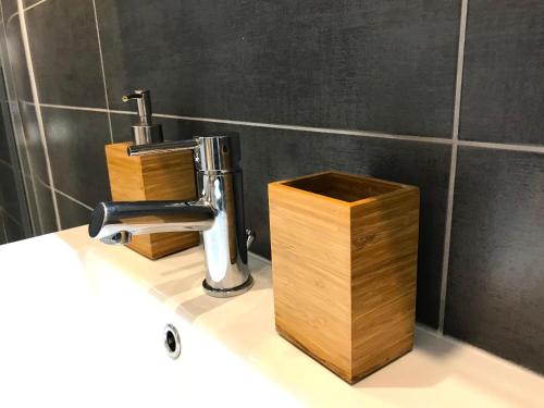 La salle de bains est pourvue d'un lavabo, d'un robinet et d'une boîte en bois. dans l'établissement Appart' 2 pièces Orléans Centre avec Cuisine, à Orléans