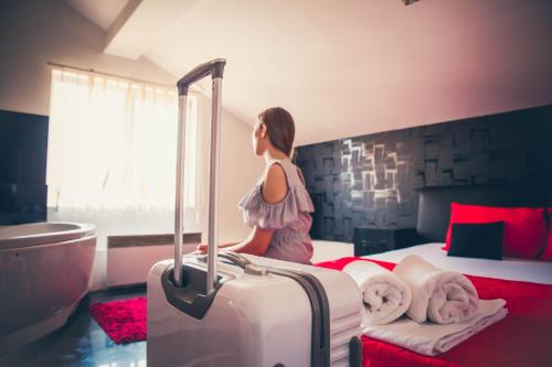 a woman is standing next to a bed with a suitcase at Guest House Vila Salute in Niš