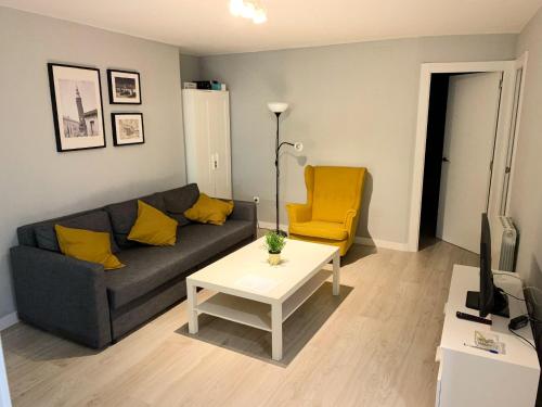 a living room with a couch and a table and a yellow chair at Apto Isabel Centro Histórico in Zaragoza