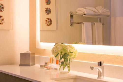 a bathroom with a vase of flowers on a sink at Gateway Hotel Santa Monica in Los Angeles