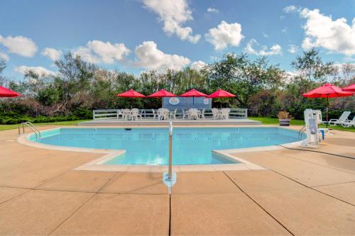 einen Pool mit roten Sonnenschirmen sowie einem Tisch und Stühlen in der Unterkunft Island Inn in Oak Bluffs
