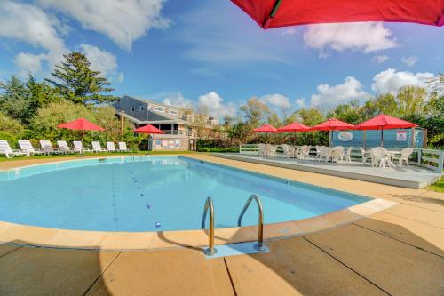 una piscina con sillas y sombrillas rojas en Island Inn, en Oak Bluffs