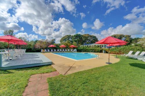 una piscina con sombrillas y sillas rojas en Island Inn, en Oak Bluffs