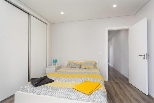 - une chambre avec un lit et une couverture jaune dans l'établissement A.V Holidays, à Fernão Ferro