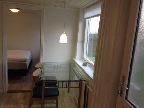um pequeno quarto com uma mesa de vidro e uma janela em Appartment Glóm C em Tórshavn
