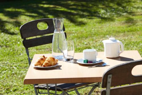 a table with a plate of croissants and a bottle of water at Campanile Montbéliard - Sochaux in Sochaux
