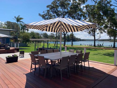 a table and chairs under an umbrella on a deck at Laguna lodge Group Accommodation in Sussex inlet