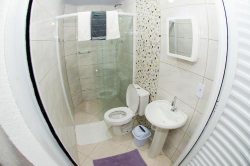 a bathroom with a shower and a toilet and a sink at PÉROLA SUÍTES - PENHA in Penha