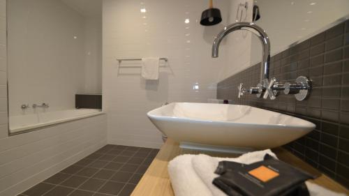 a bathroom with a sink and a bath tub at The Astor Suites in Goulburn