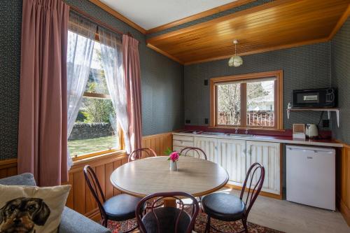 een keuken met een tafel en stoelen en een tafel en een raam bij Settlers Cottage Motel in Arrowtown