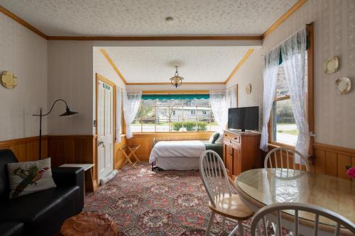a living room with a table and a bedroom at Settlers Cottage Motel in Arrowtown